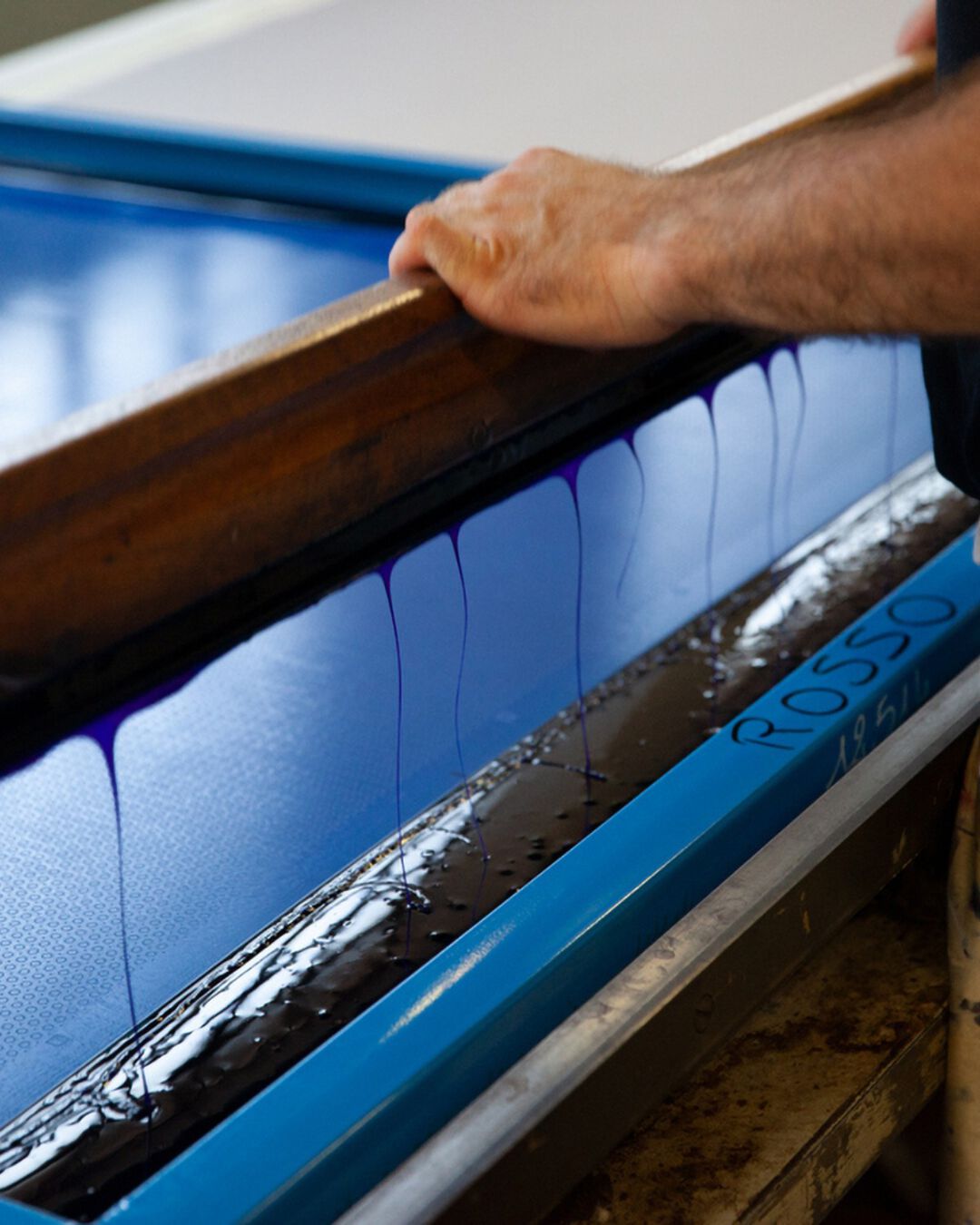 For each colour they make two passes, using a squeegee to push the pigment through the frame. Their movements must be perfectly synchronised, applying equal pressure to ensure consistency.