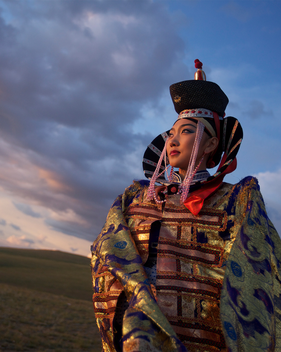 A Mongolian woman wearing the traditional costume. The landscapes are characterised by infinite pastures and horizons.