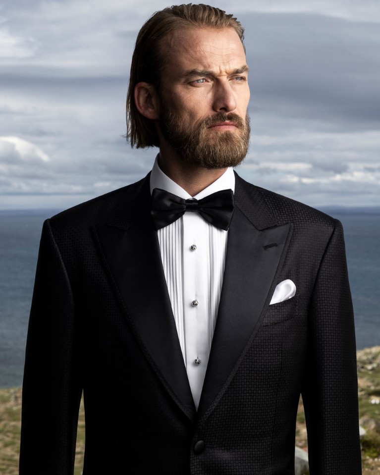 Lukas is wearing a refined one-button tuxedo in silk and wool paired with an evening shirt with pleated plastron and silk bow tie.