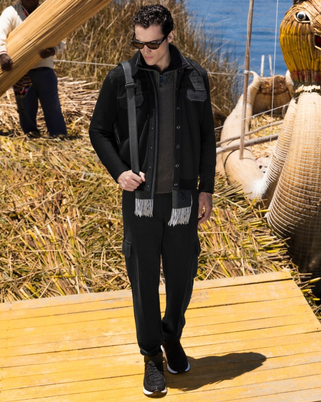 The model wears a cashmere, wool and silk blouson with crocodile inserts paired with a zip mock neck sweater and knit cargo trousers, both in fine wool and silk.