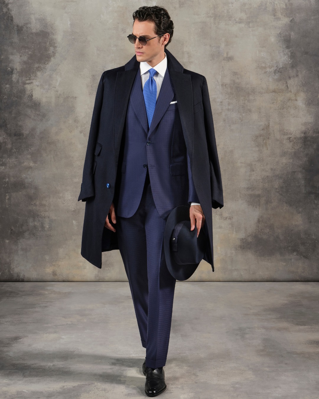 The model wears a deconstructed two-button coat in vicuna and cashmere over a Fiesole suit in fine wool.